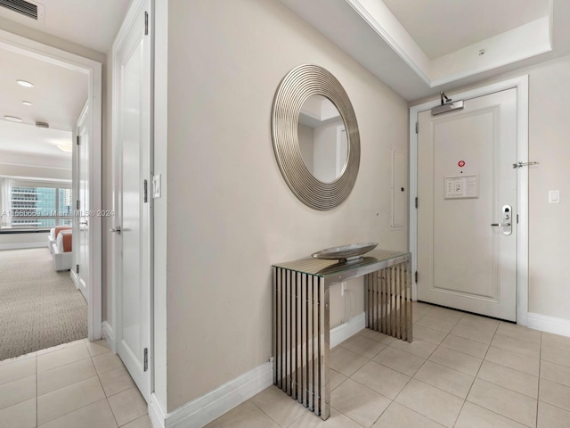 entrance foyer featuring a tray ceiling and light tile patterned floors