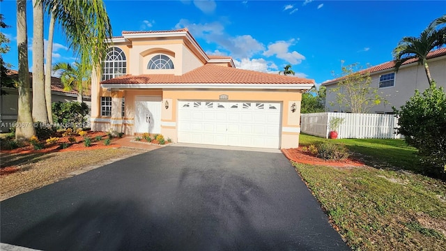 mediterranean / spanish-style house featuring aphalt driveway, stucco siding, a tile roof, and fence