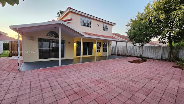 rear view of property with a patio area, stucco siding, and fence