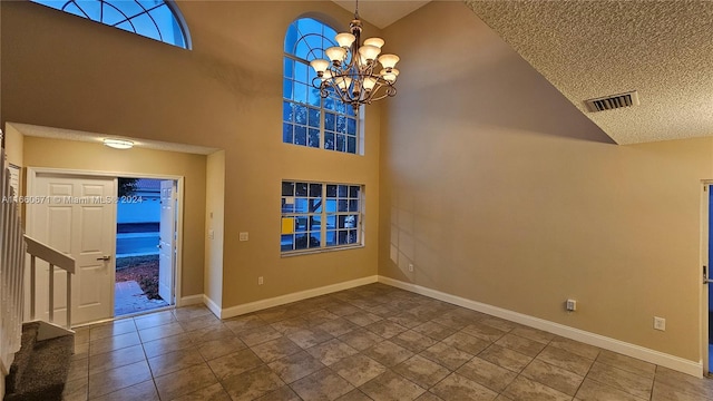 entryway with a textured ceiling, tile patterned flooring, a chandelier, and high vaulted ceiling