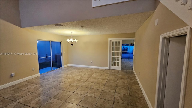 unfurnished room featuring a textured ceiling, tile patterned flooring, and a chandelier