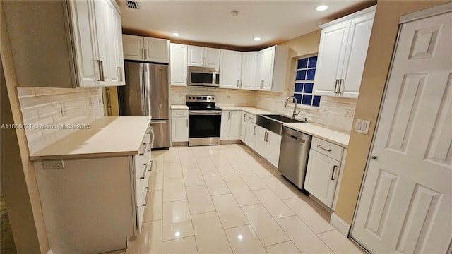 kitchen featuring a sink, decorative backsplash, white cabinetry, and stainless steel appliances