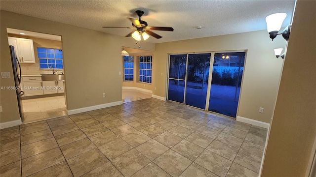 empty room with a textured ceiling, ceiling fan, light tile patterned flooring, and sink