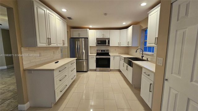 kitchen with stainless steel appliances, white cabinetry, tasteful backsplash, and sink