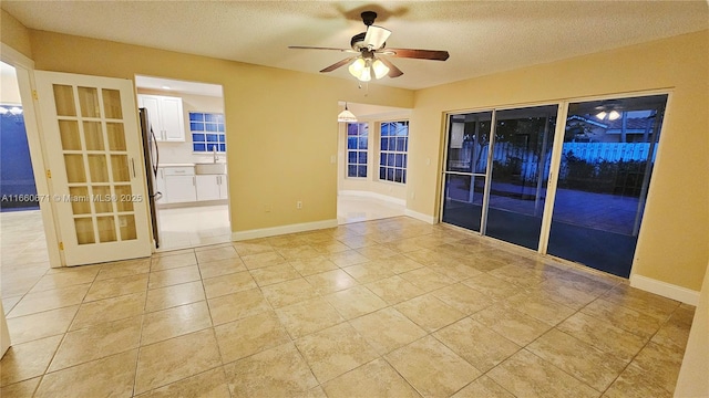 spare room with baseboards, ceiling fan, light tile patterned floors, a textured ceiling, and a sink