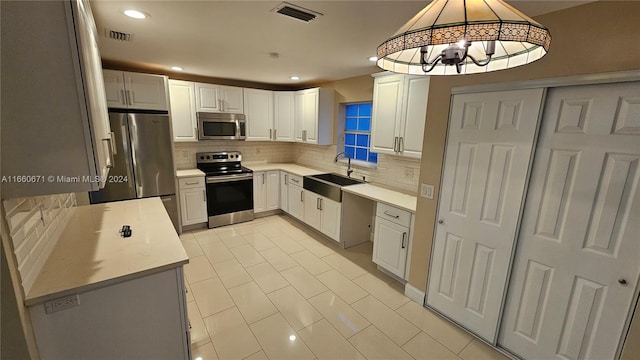 kitchen featuring sink, white cabinets, hanging light fixtures, an inviting chandelier, and stainless steel appliances