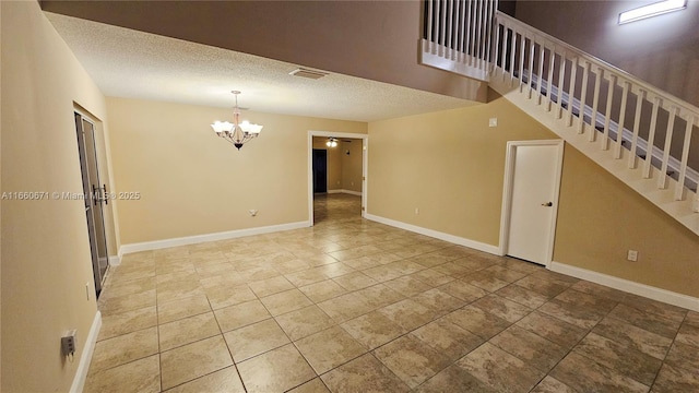 tiled spare room featuring stairs, baseboards, visible vents, and a textured ceiling