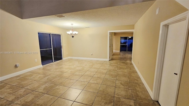 spare room featuring visible vents, baseboards, an inviting chandelier, light tile patterned flooring, and a textured ceiling