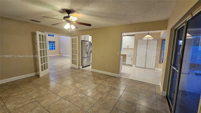 tiled empty room featuring a textured ceiling and ceiling fan