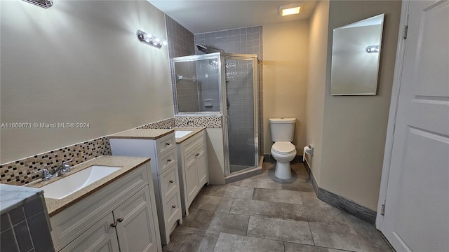 bathroom with backsplash, vanity, a shower with shower door, and toilet