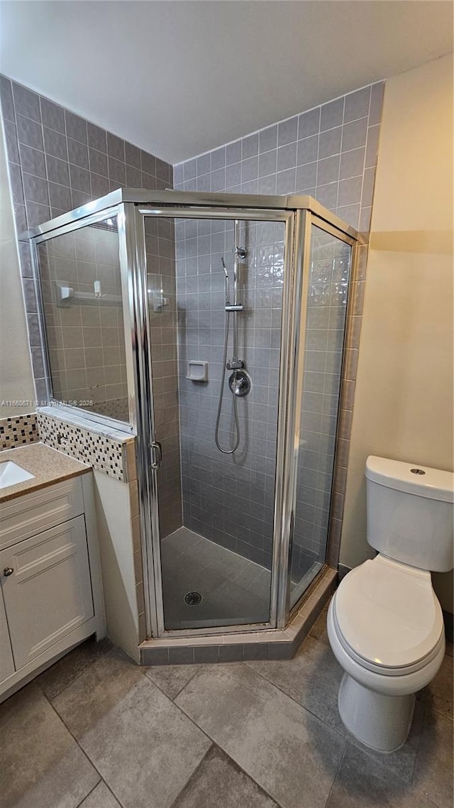 bathroom with tile patterned floors, vanity, toilet, and a shower stall