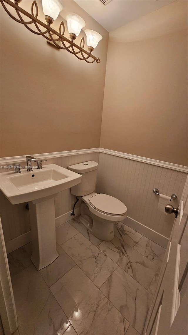 bathroom featuring wood walls and toilet