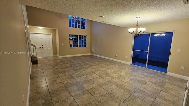 tiled spare room with a textured ceiling and a chandelier