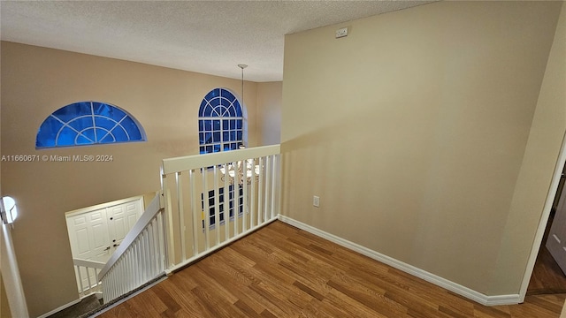 hall with a textured ceiling and hardwood / wood-style flooring