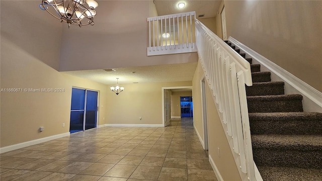 staircase with a high ceiling, a chandelier, a textured ceiling, and tile patterned floors