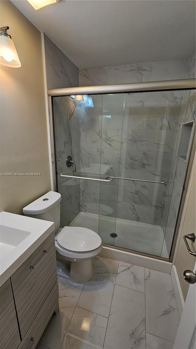 bathroom featuring a shower with shower door, vanity, and toilet