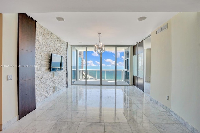 spare room with expansive windows and an inviting chandelier