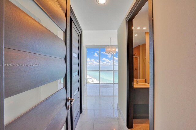 hall featuring floor to ceiling windows, a notable chandelier, and sink