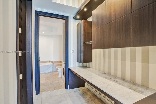 bathroom with a tub, toilet, and tile patterned floors