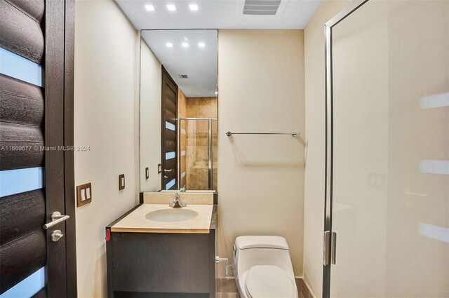 bathroom featuring vanity, toilet, and a shower with shower door