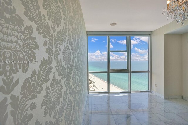 unfurnished room with a healthy amount of sunlight, a wall of windows, and a water view