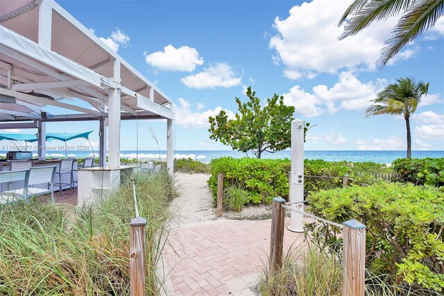 view of property's community with a patio area, a beach view, and a water view