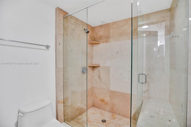 bathroom featuring toilet and a shower with shower door