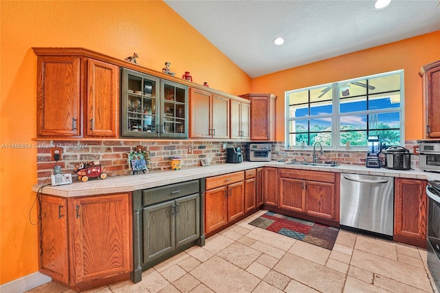 kitchen featuring stainless steel dishwasher, sink, black electric range, tile counters, and lofted ceiling