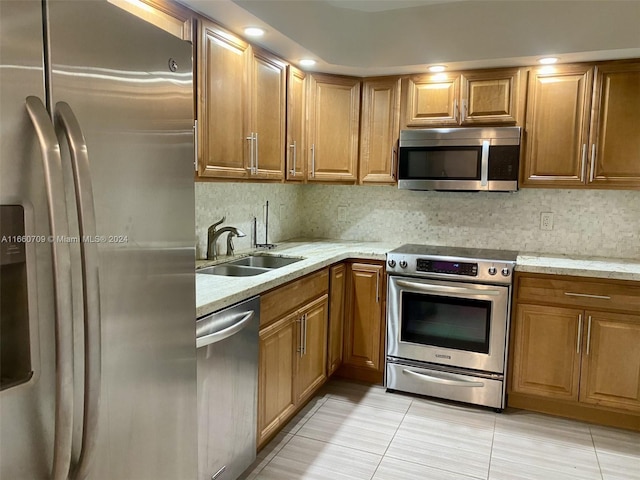 kitchen with light tile patterned floors, sink, backsplash, appliances with stainless steel finishes, and light stone countertops