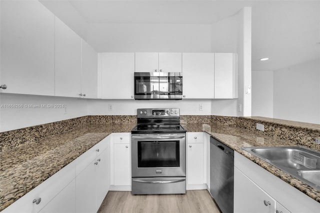 kitchen featuring dark stone countertops, white cabinetry, stainless steel appliances, and light hardwood / wood-style flooring