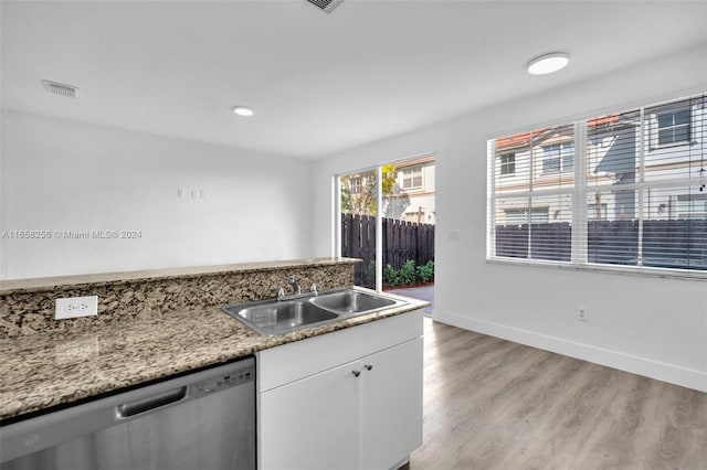 kitchen featuring sink, light hardwood / wood-style flooring, stainless steel dishwasher, light stone counters, and white cabinetry