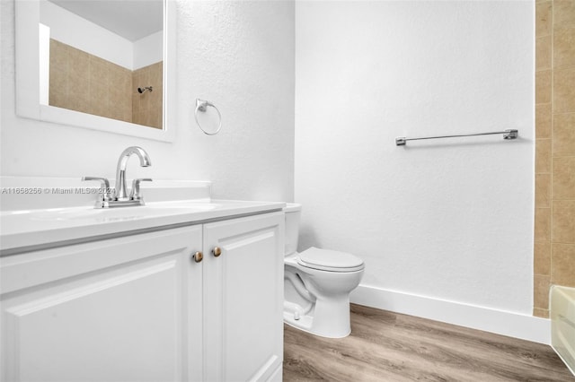 full bathroom with vanity, hardwood / wood-style flooring, toilet, and tiled shower / bath