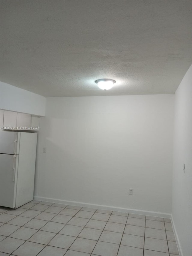 empty room featuring a textured ceiling and light tile patterned floors