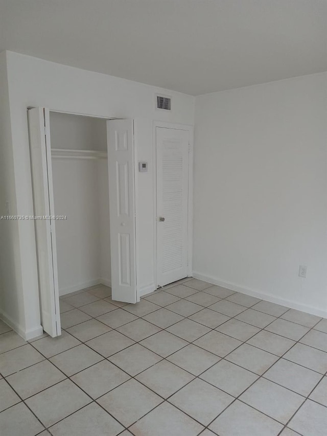 unfurnished bedroom featuring a closet and light tile patterned floors