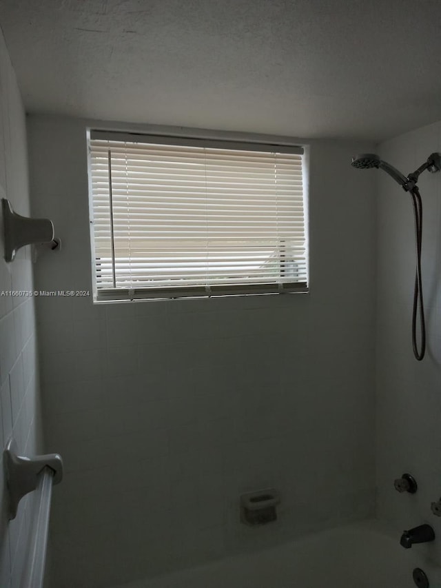 bathroom featuring a textured ceiling and tiled shower / bath combo