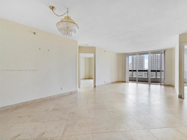 unfurnished room with an inviting chandelier, floor to ceiling windows, and light tile patterned floors