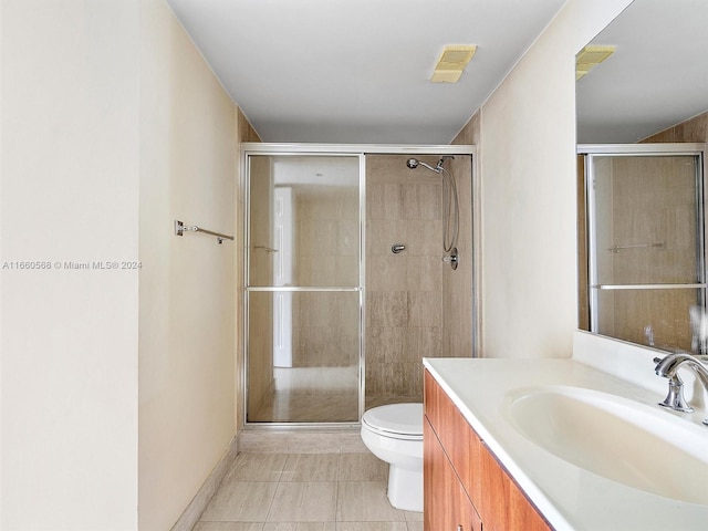 bathroom with vanity, a shower with shower door, toilet, and tile patterned flooring