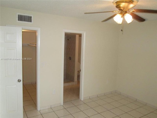 tiled empty room featuring ceiling fan and a textured ceiling