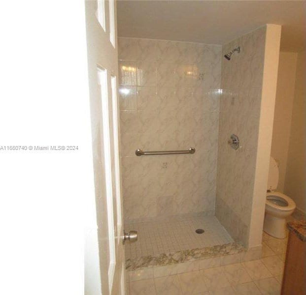 bathroom featuring tile patterned floors, toilet, and tiled shower