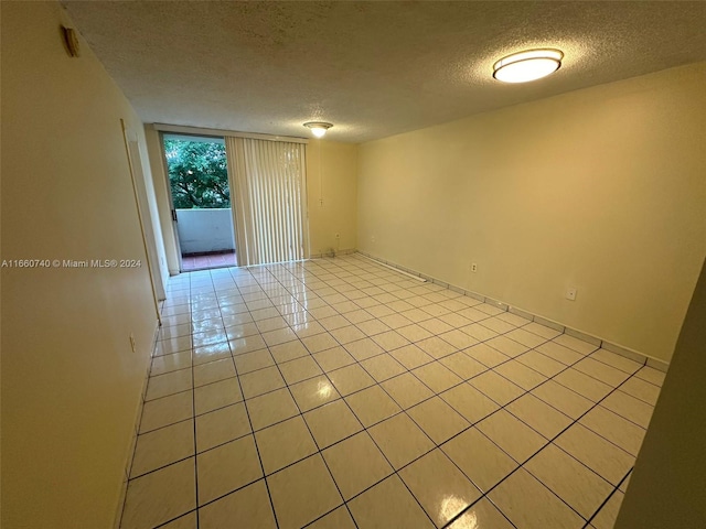 tiled empty room featuring a textured ceiling