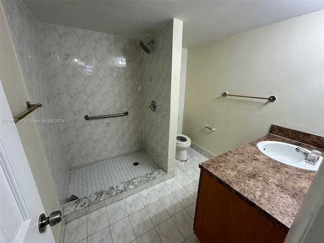 bathroom featuring tiled shower, vanity, toilet, and tile patterned flooring