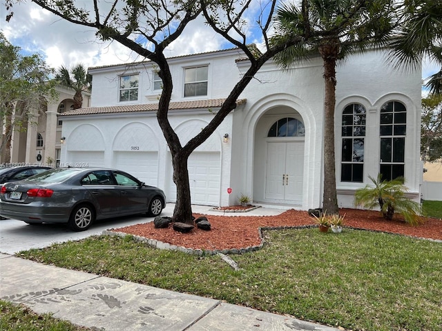 mediterranean / spanish home featuring a garage and a front lawn