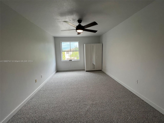 spare room featuring ceiling fan, light colored carpet, and a textured ceiling