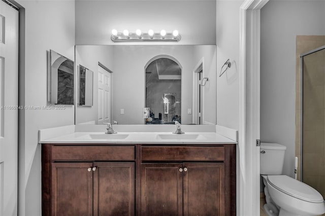 bathroom featuring vanity, toilet, and a shower with door