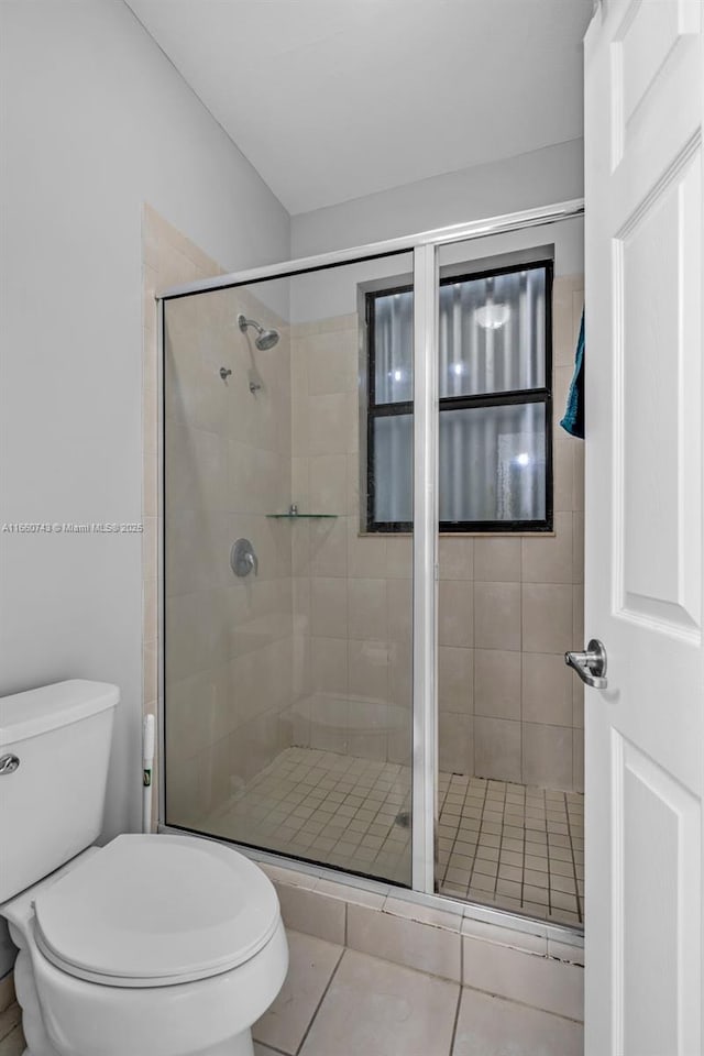 bathroom with tile patterned floors, a shower with shower door, and toilet