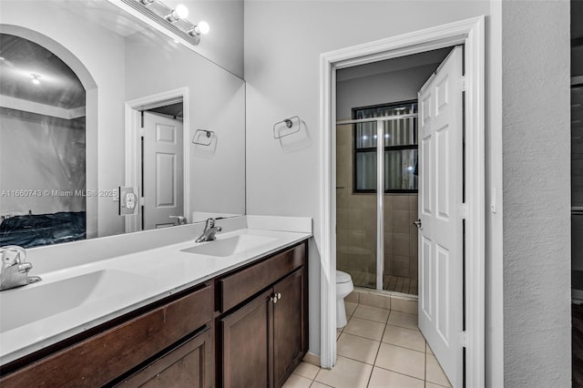 bathroom featuring tile patterned flooring, vanity, a shower with door, and toilet