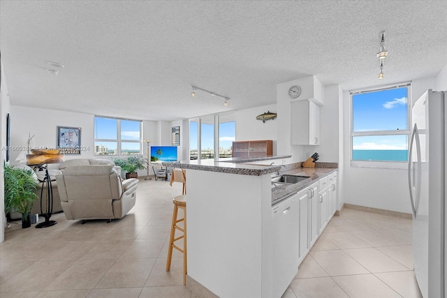 kitchen with a kitchen breakfast bar, white cabinetry, white appliances, kitchen peninsula, and track lighting