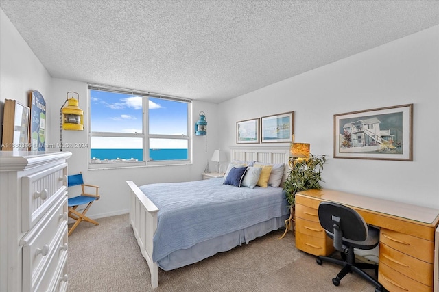 carpeted bedroom with a water view and a textured ceiling