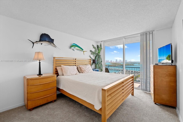 carpeted bedroom with access to outside, a textured ceiling, and floor to ceiling windows