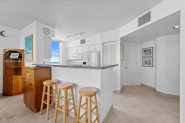 kitchen with a kitchen breakfast bar, white cabinets, white appliances, kitchen peninsula, and a textured ceiling